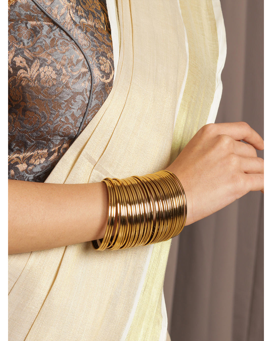 Model wearing Fida set of 18 gold-plated metal bangles for women—sleek traditional Indian jewellery stack