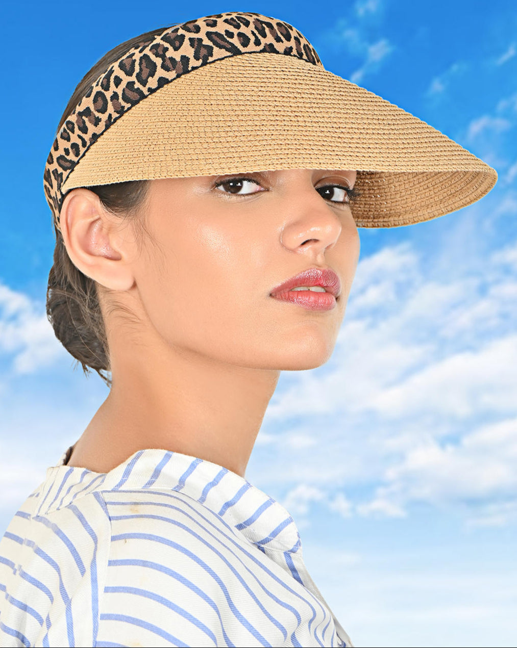 A woman wearing a tan beach sun visor hat with a tiger print band.