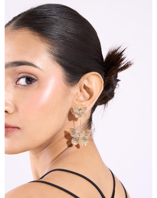 A woman wearing gold-plated alloy butterfly twin dangler earrings with pearl embellishments.