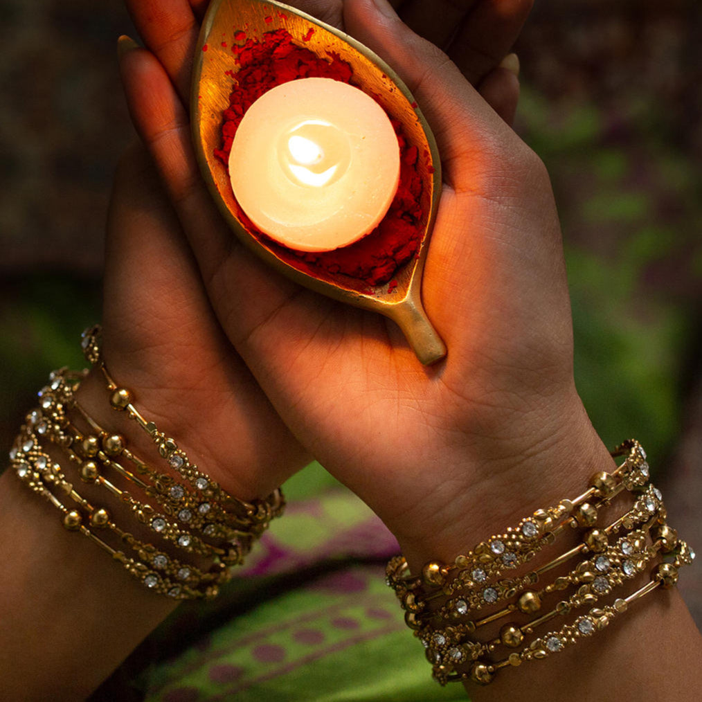 Set of 12 gold-plated metal bangles with sparkling stones and beads. Perfect ethnic jewellery for weddings, parties & traditional celebrations.