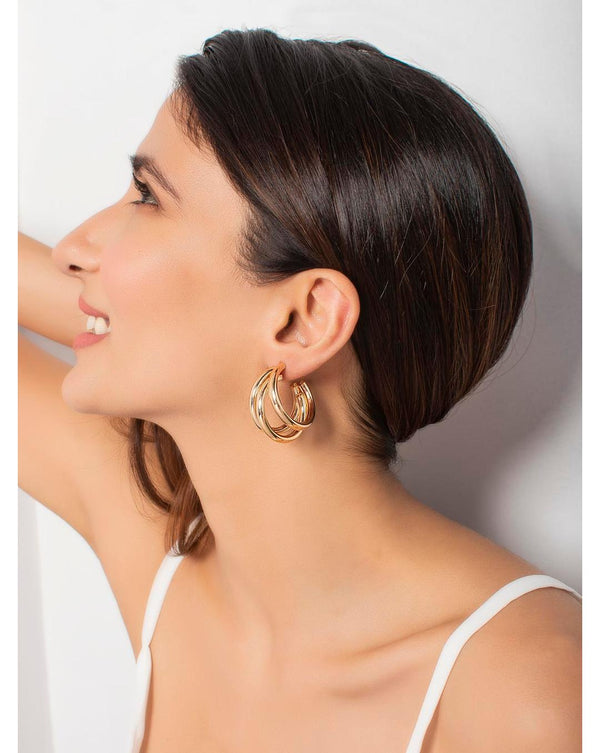 A woman wearing Harmony Gold Hoop Earrings with a polished finish.