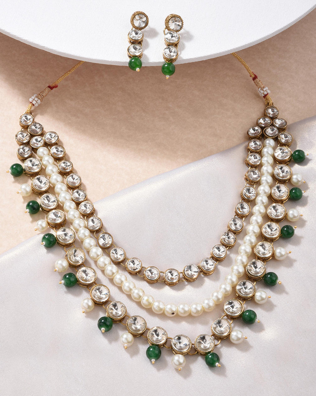 a gold plated necklace with green pearl beaded layers and matching earrings.