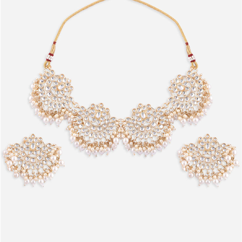 a traditional Indian ethnic gold and white pearl kundan choker necklace, earrings, and maang tikka set.