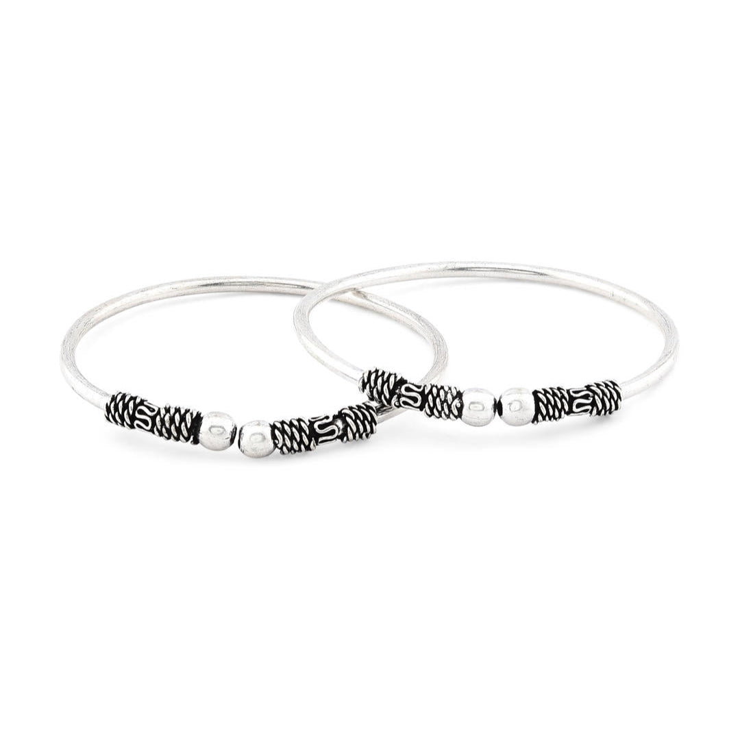 A silver-plated oxidised bangle set, featuring intricate detailing and a textured look with white background.