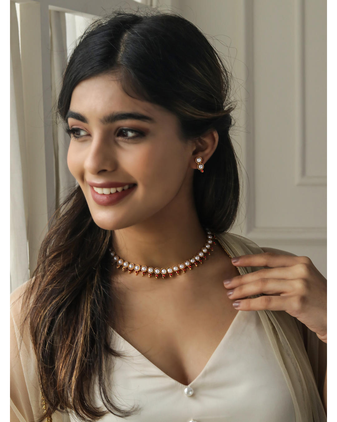 a gold-plated necklace and earrings set with white pearls and fuchsia stones.