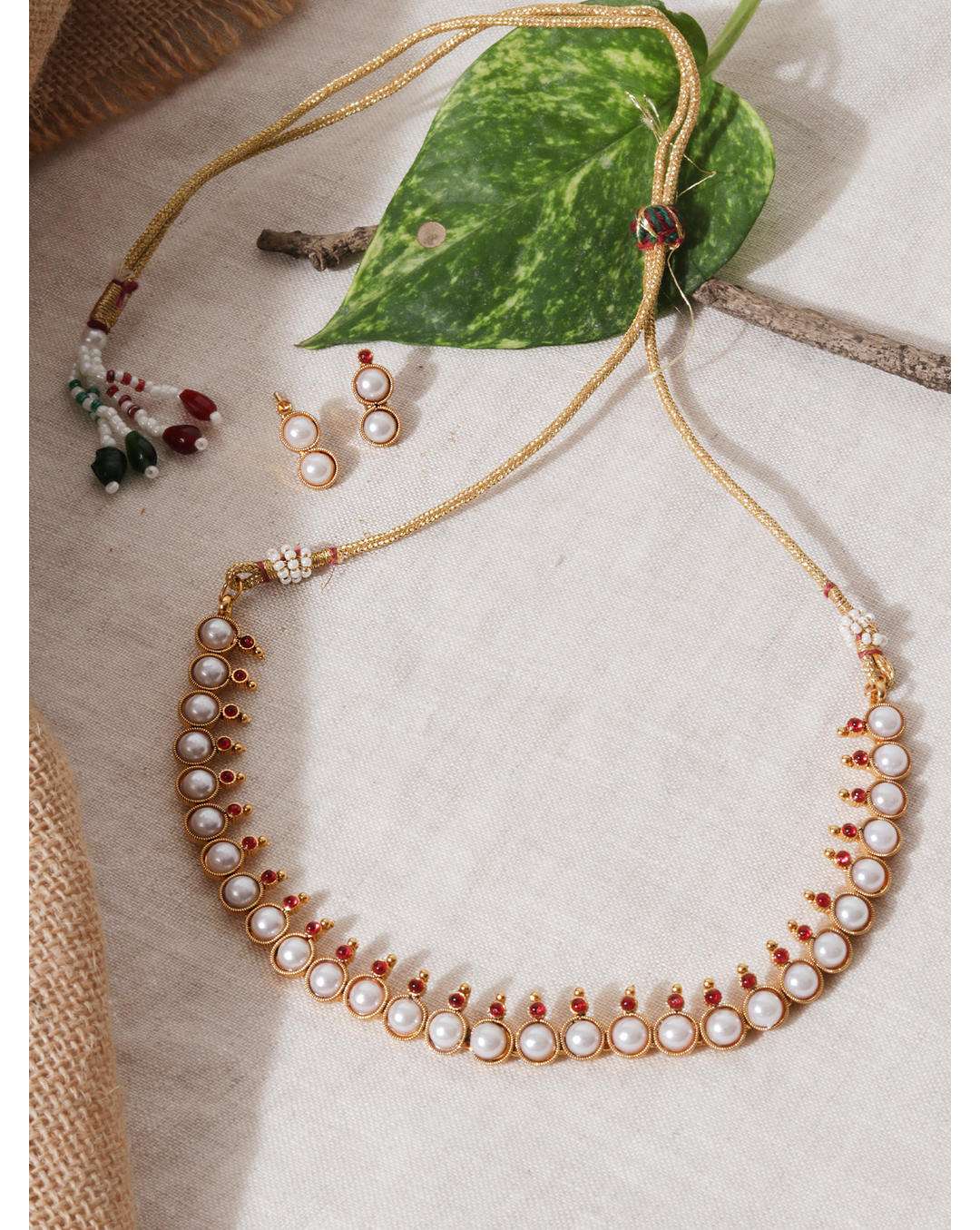 a gold-plated necklace and earrings set with white pearls and fuchsia stones.