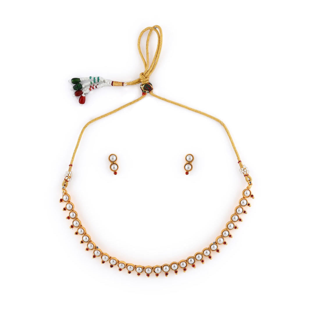 a gold-plated necklace and earrings set with white pearls and fuchsia stones.