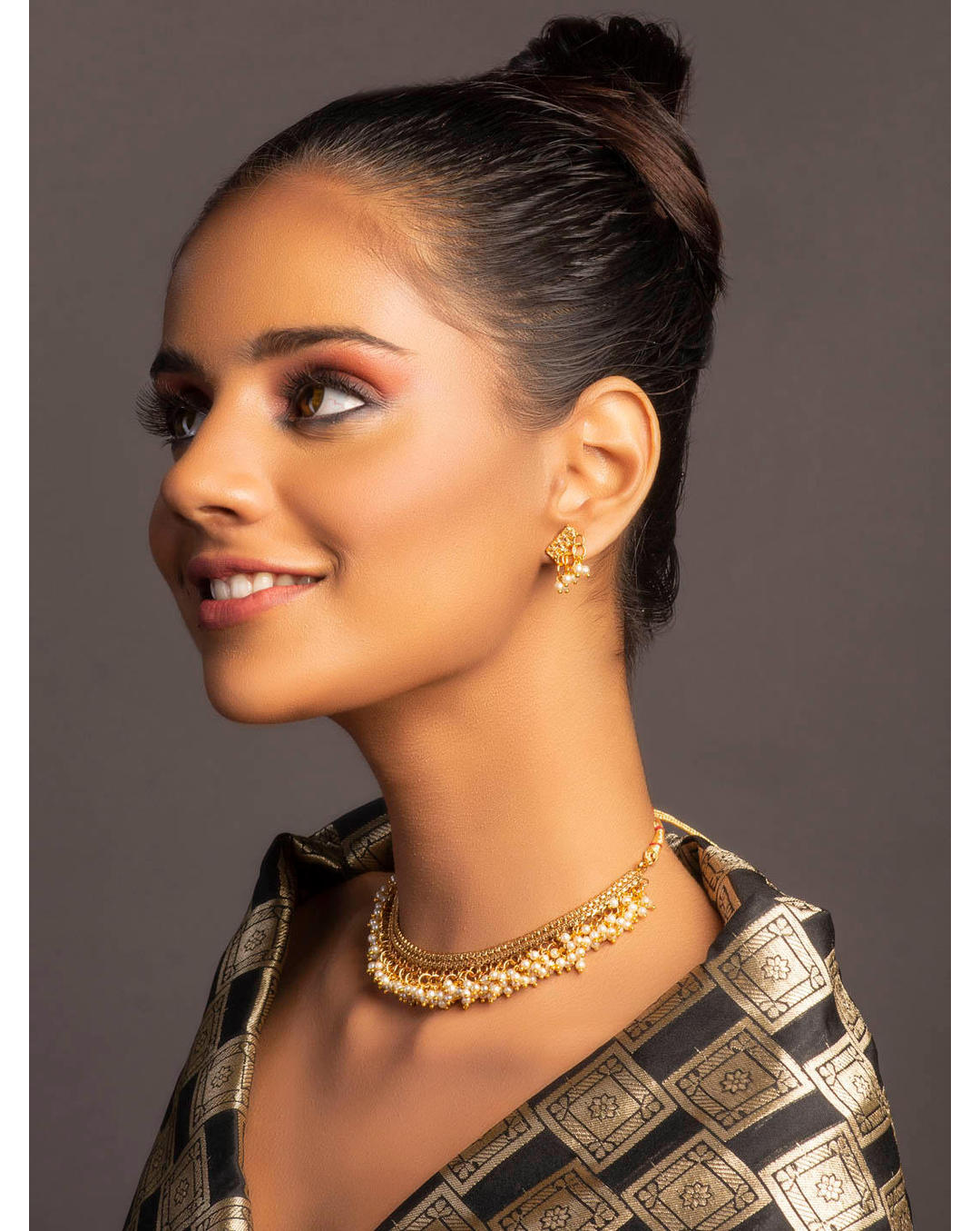 a gold-plated necklace with white beads, along with matching earrings, showcasing a piece of temple jewellery.