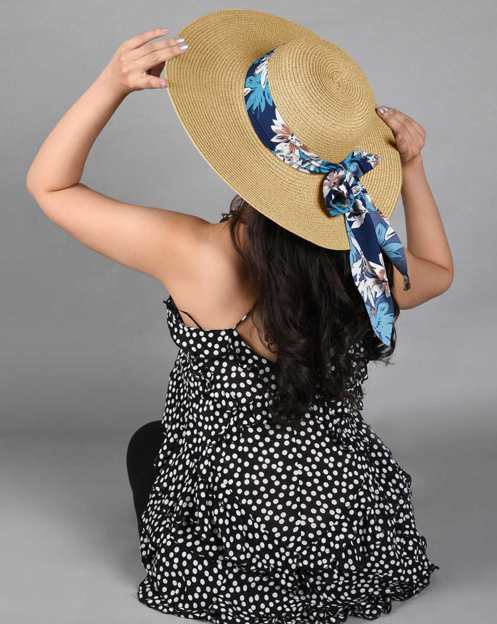 Female Model wearing A beige beach hat with a blue floral scarf tied around the base.