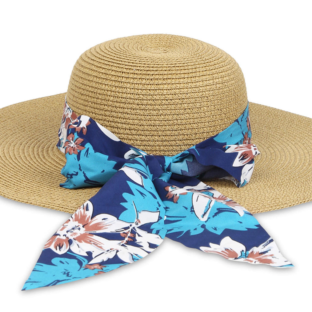 A straw beach hat with a navy printed scarf around the brim close-up