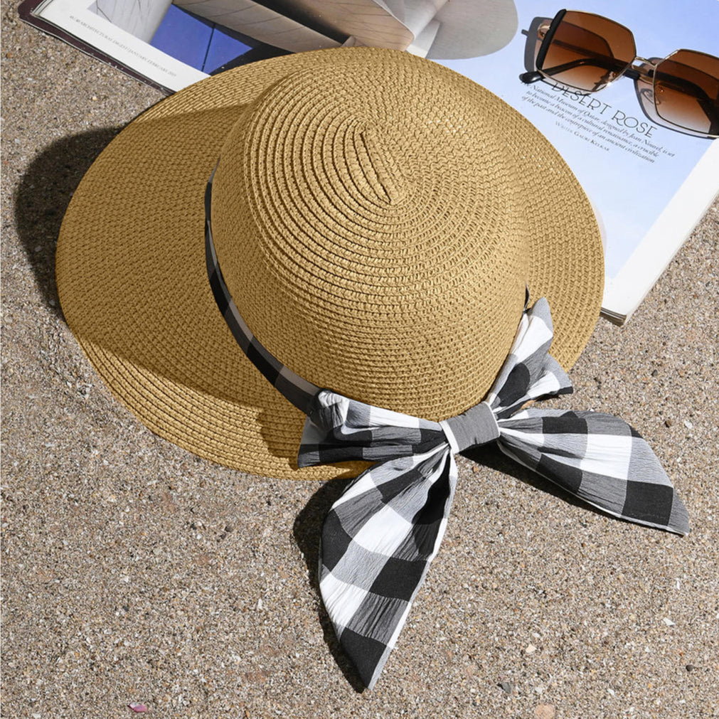 A beige beach hat with a black-and-white checked scarf tied around the base.