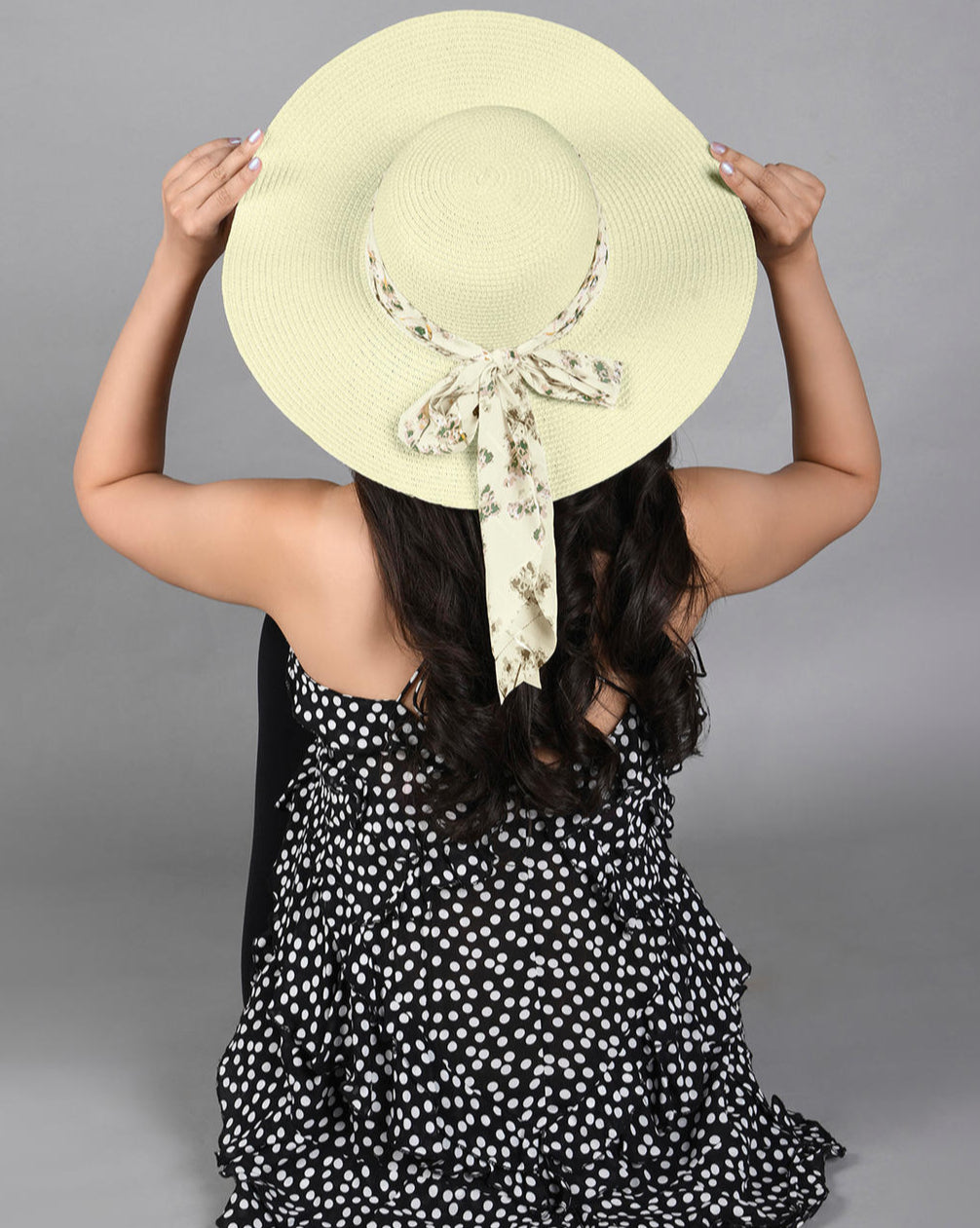 A white beach hat with an ivory floral scarf tied around the brim.