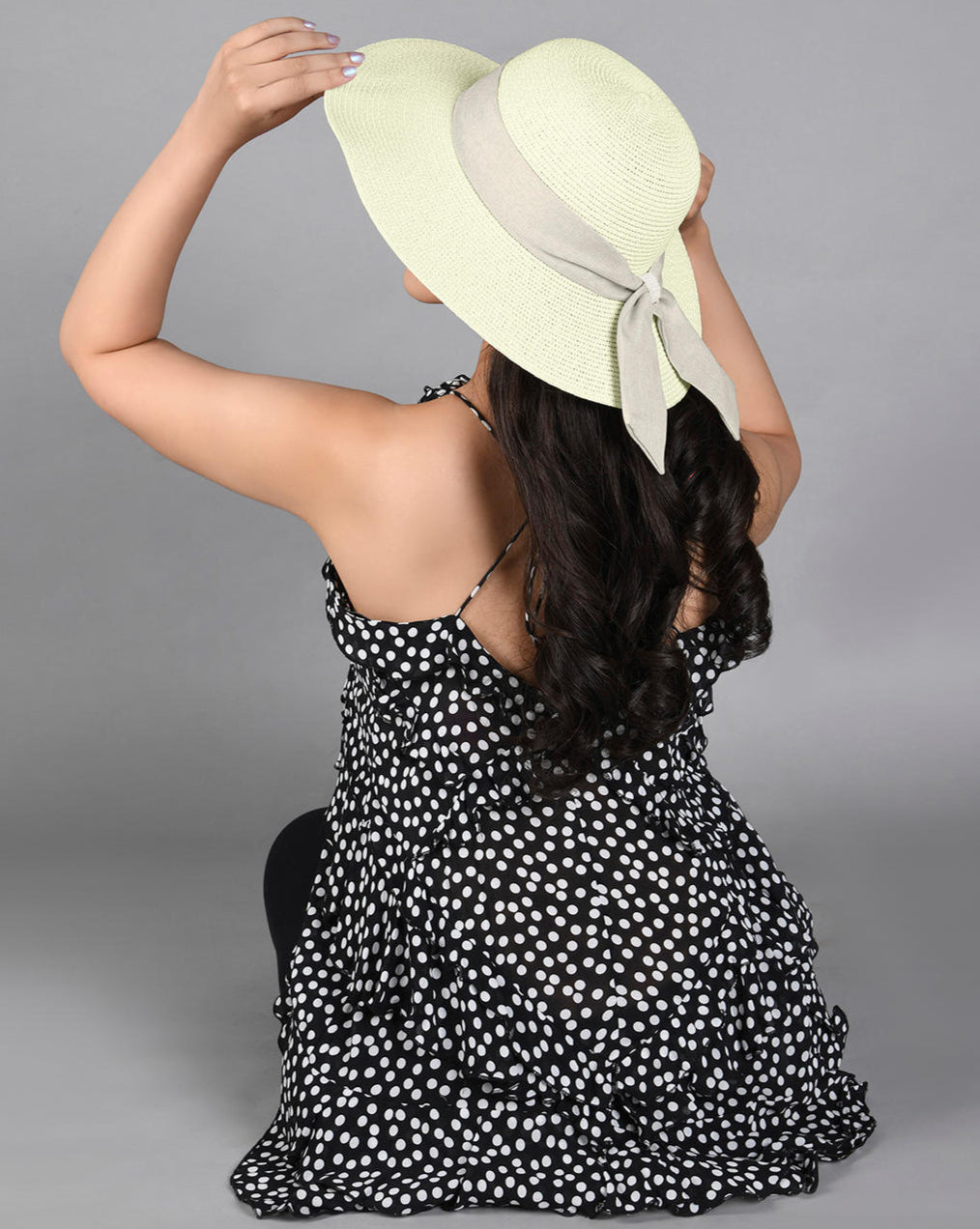 women wearing A white beach hat with a tan scarf tied around the base, made from woven straw material.