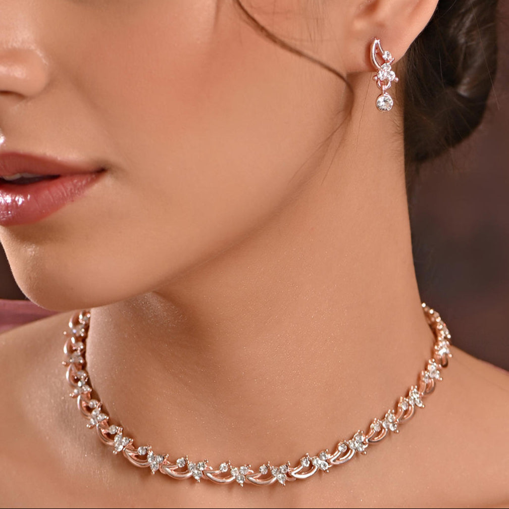A woman wearing a luxurious rose gold and American diamond floral party jewellery set, including a necklace and earrings.