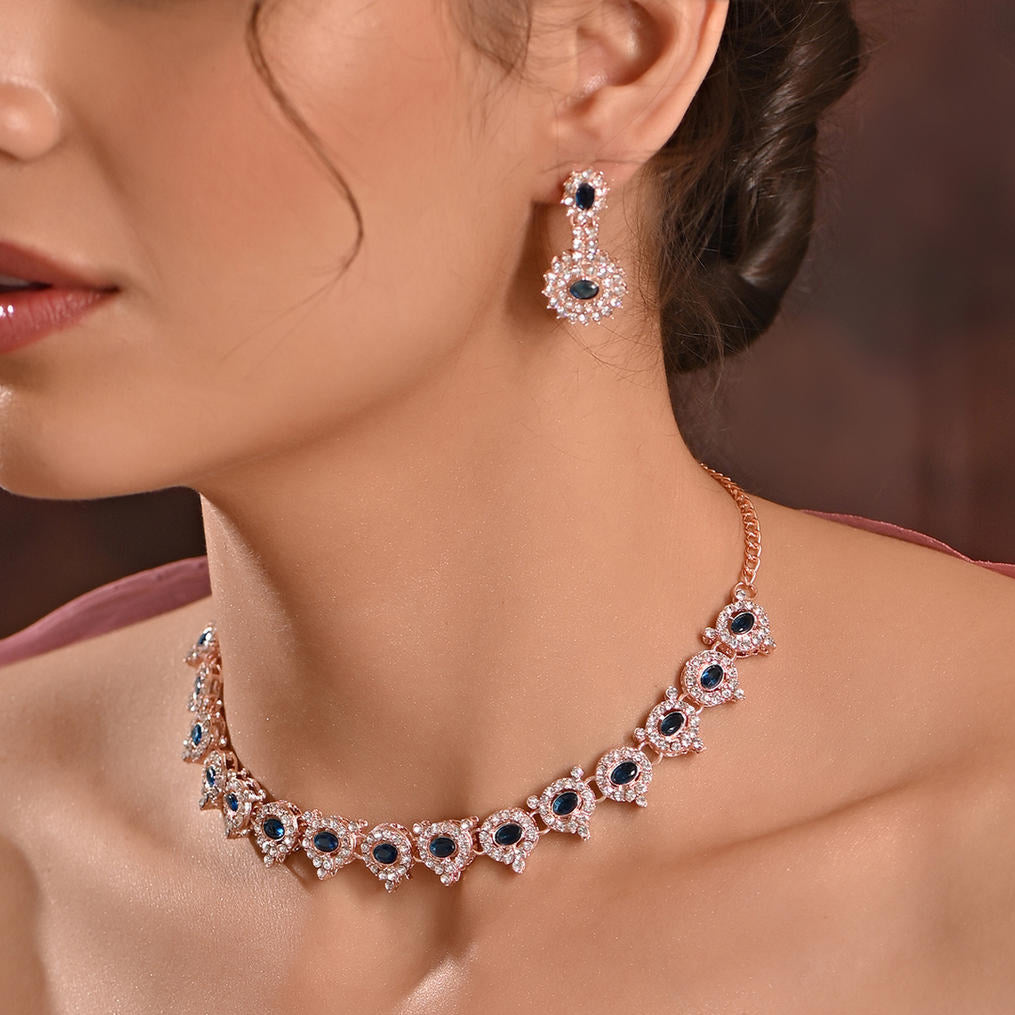 A woman wearing a luxurious sapphire blue floral wedding jewellery set, including a matching necklace and earrings.