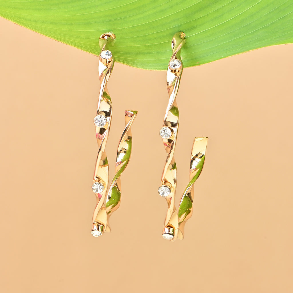 Gold earrings with diamond-like stones on a beige and green leaf background. ToniQ jewellery is skin safe, nickel free, cadmium free, hypoallergenic, and lab tested for your comfort and trust.