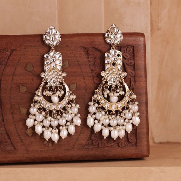 Pair of ornate earrings with pearls on a wooden surface