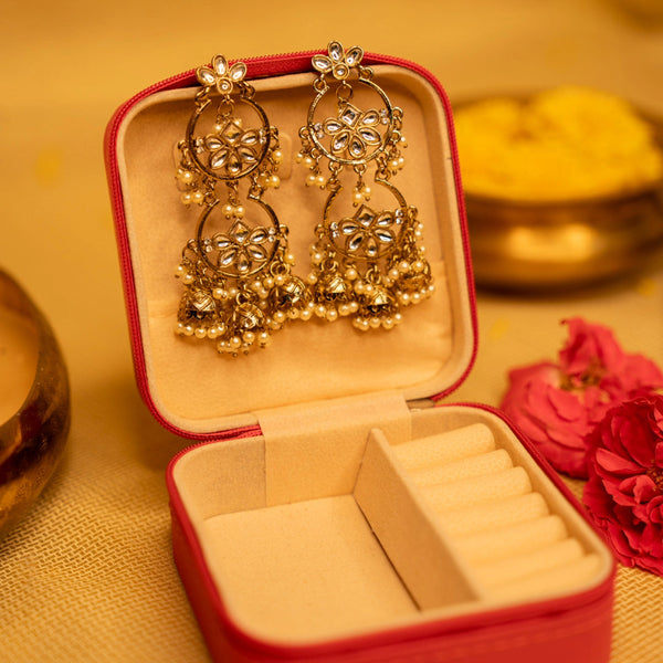 Gold earrings in a red jewelry box on a yellow background