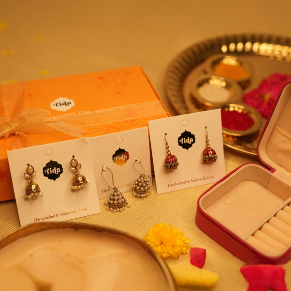 Jewelry set with earrings on cards, box, and decorative items on a table.