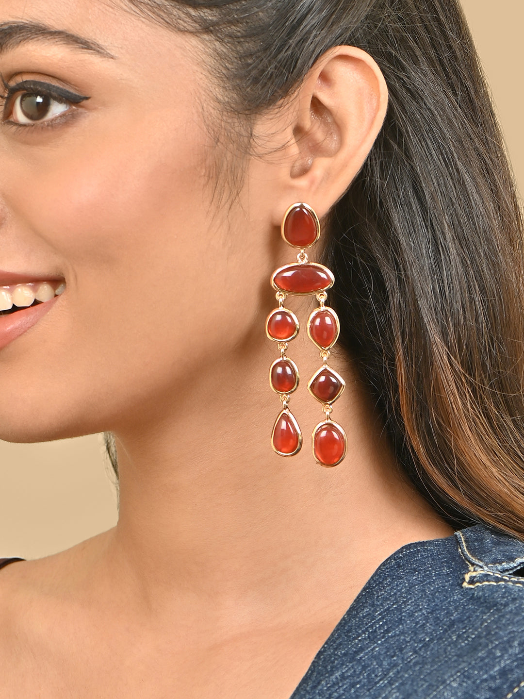 Close-up of a woman wearing red stone earrings with a beige skin safe jewellery, nickel free, cadmium free, hypoallergenic, lab tested
background