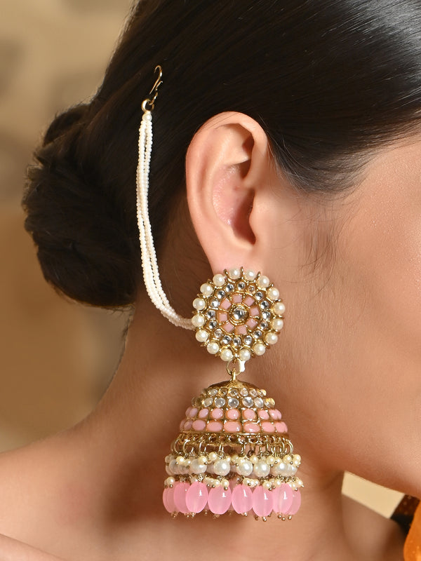 A woman's ear wearing a gold plated peach beads kundan pearl jhumka earring with intricate designs and artificial beads.