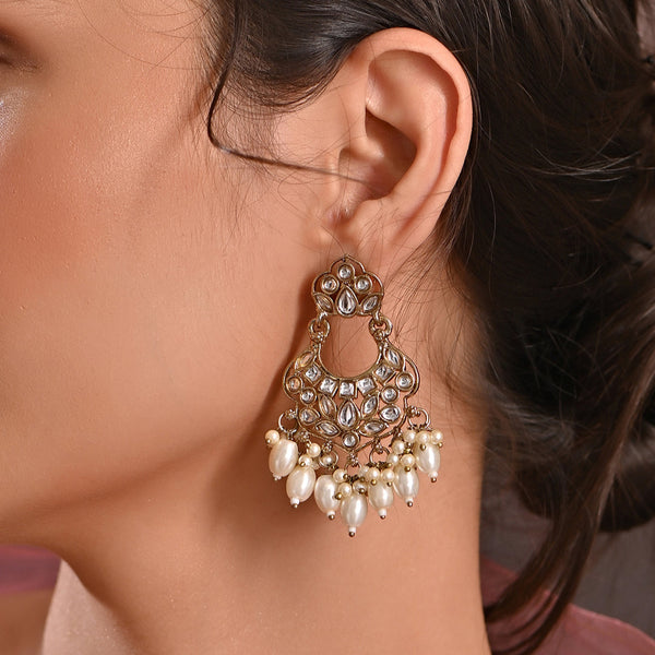 A pair of gold-plated chandbali earrings adorned with white kundan stones and pearl drops