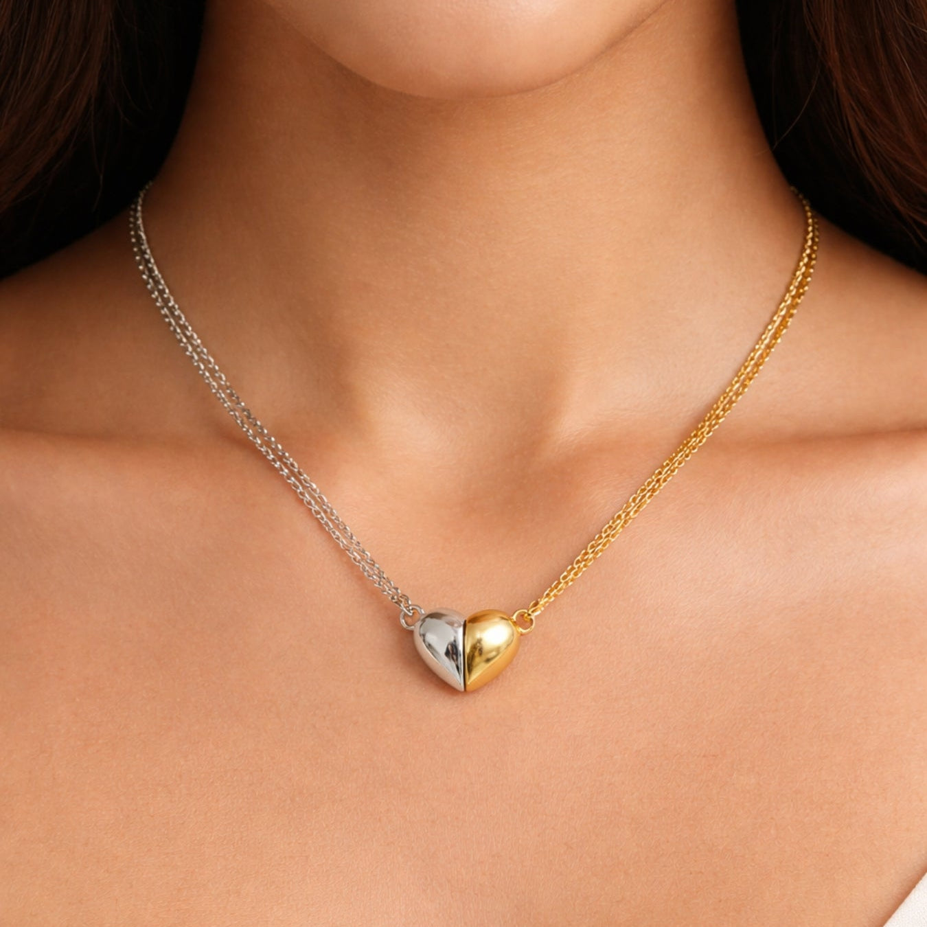 Gold and silver heart-shaped necklace on a person's neck