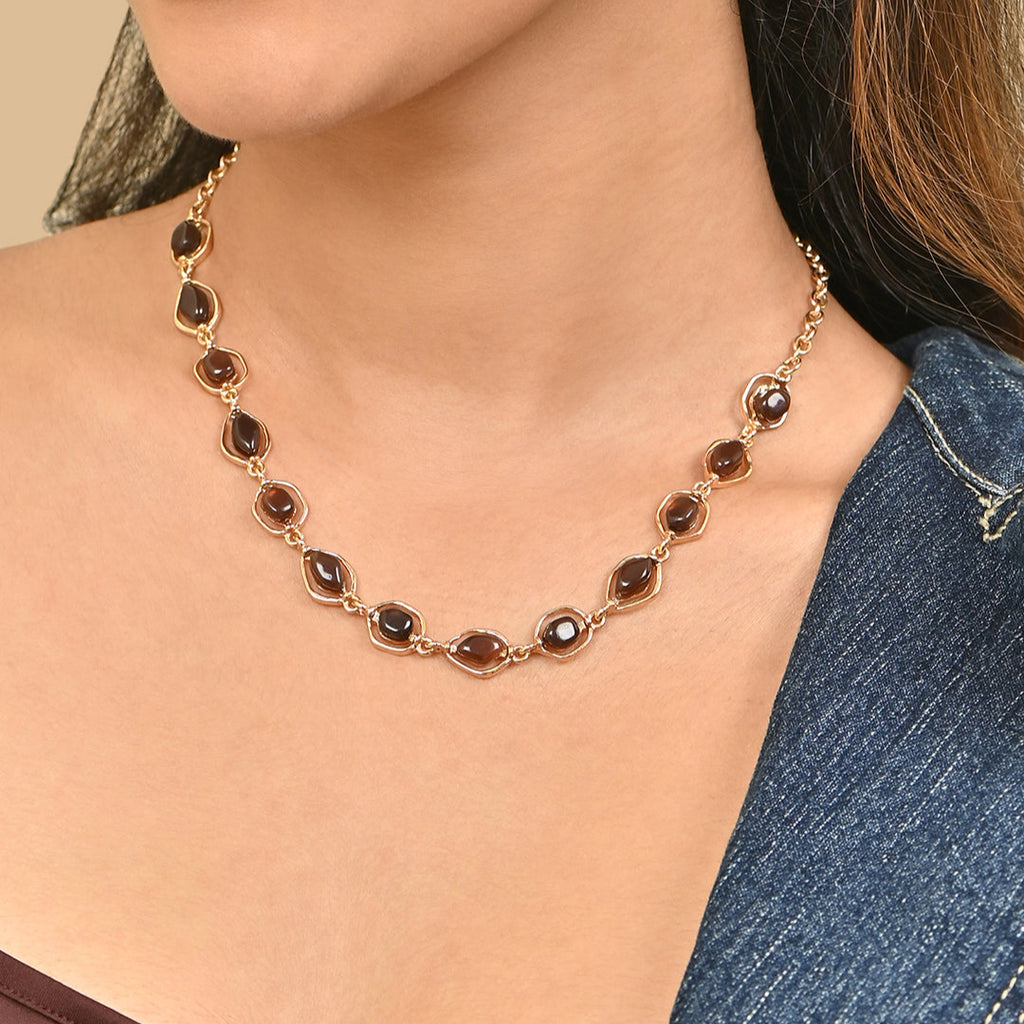 Necklace with brown gemstones worn by a person against a neutral background