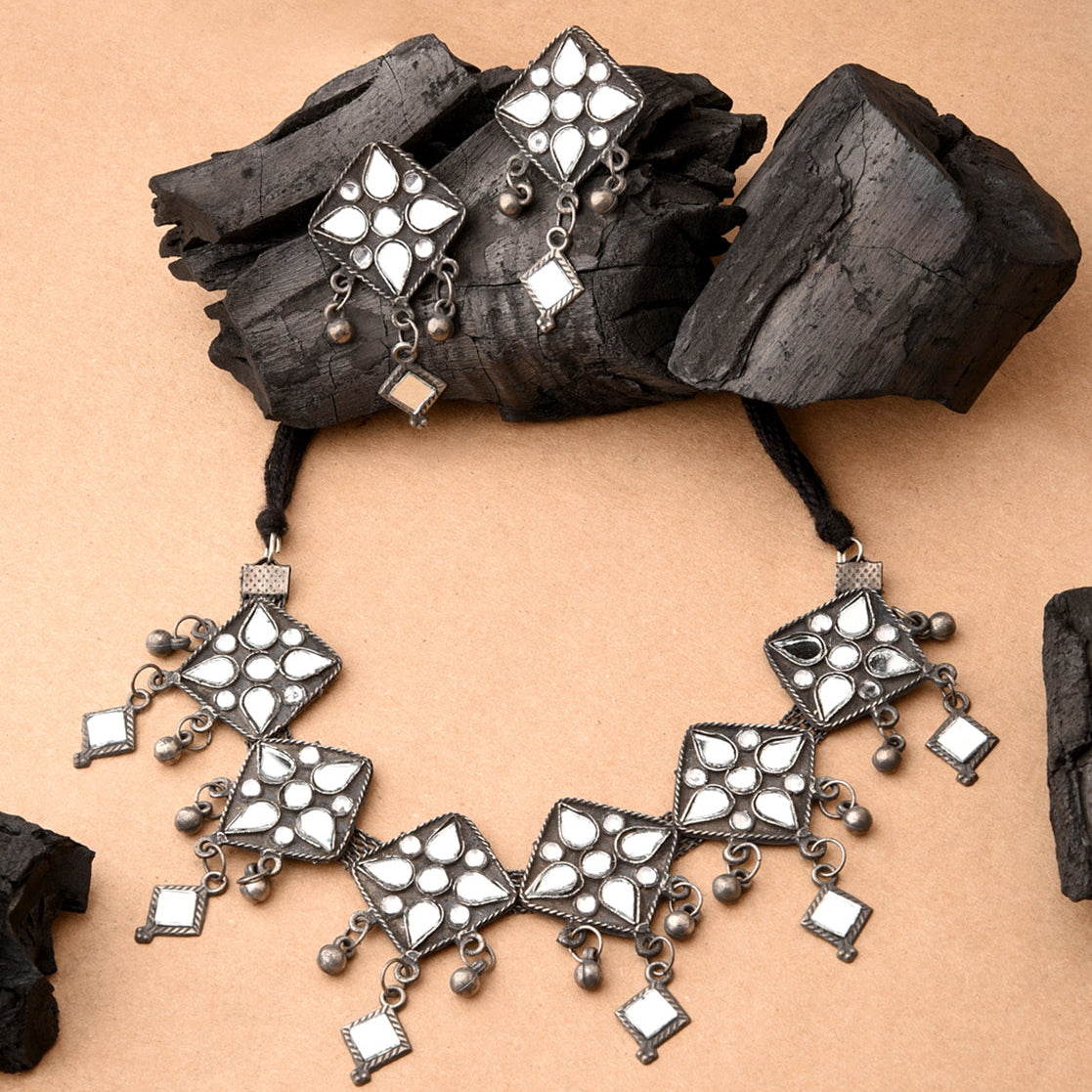 Ornate silver necklace with square designs on a beige background