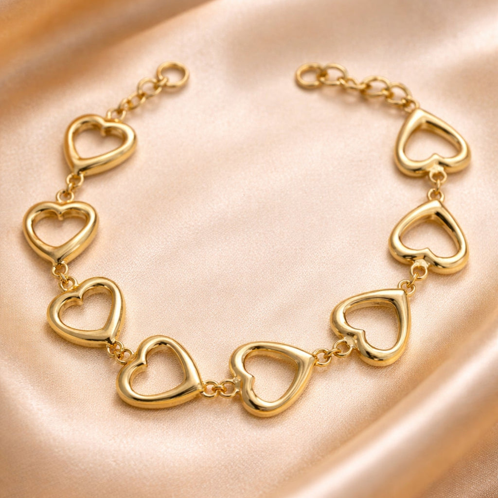 Gold heart-shaped bracelet on a soft pink fabric background