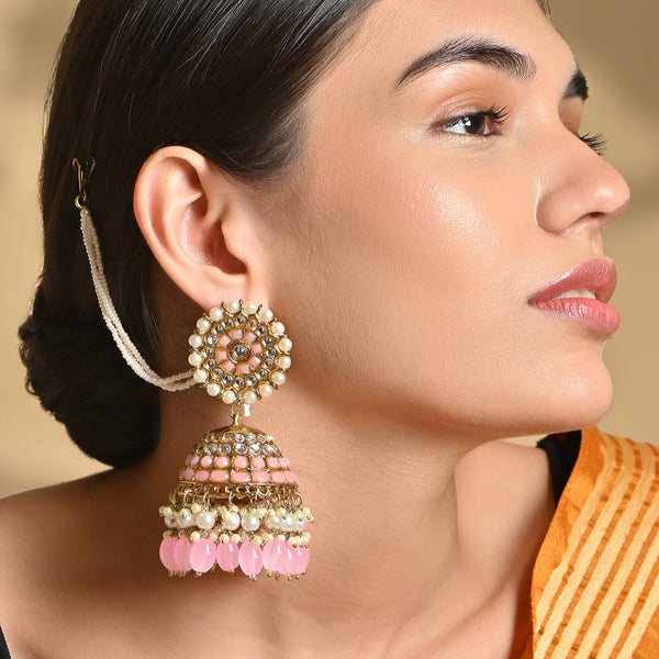A woman's ear wearing a gold plated peach beads kundan pearl jhumka earring with intricate designs and artificial beads.