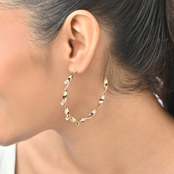 Gold hoop earring worn by a person with a blurred background. ToniQ jewellery is skin safe, nickel free, cadmium free, hypoallergenic, and lab tested for your comfort and trust.