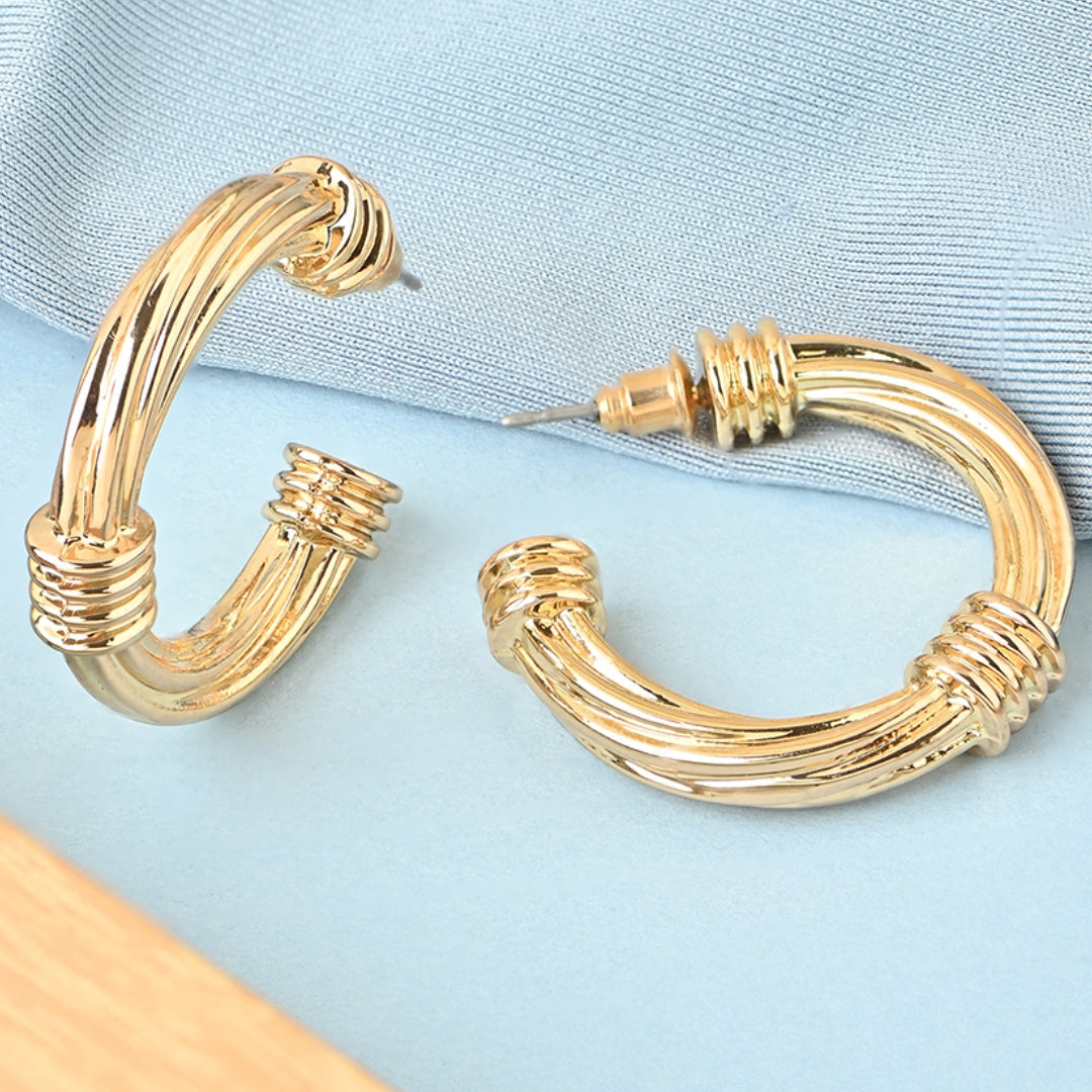 Gold hoop earrings on a light blue fabric background