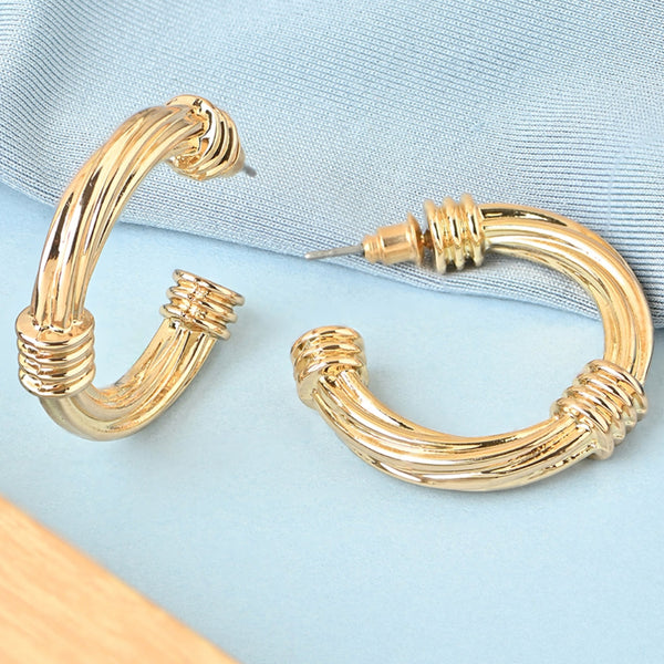 Gold hoop earrings on a light blue fabric background
