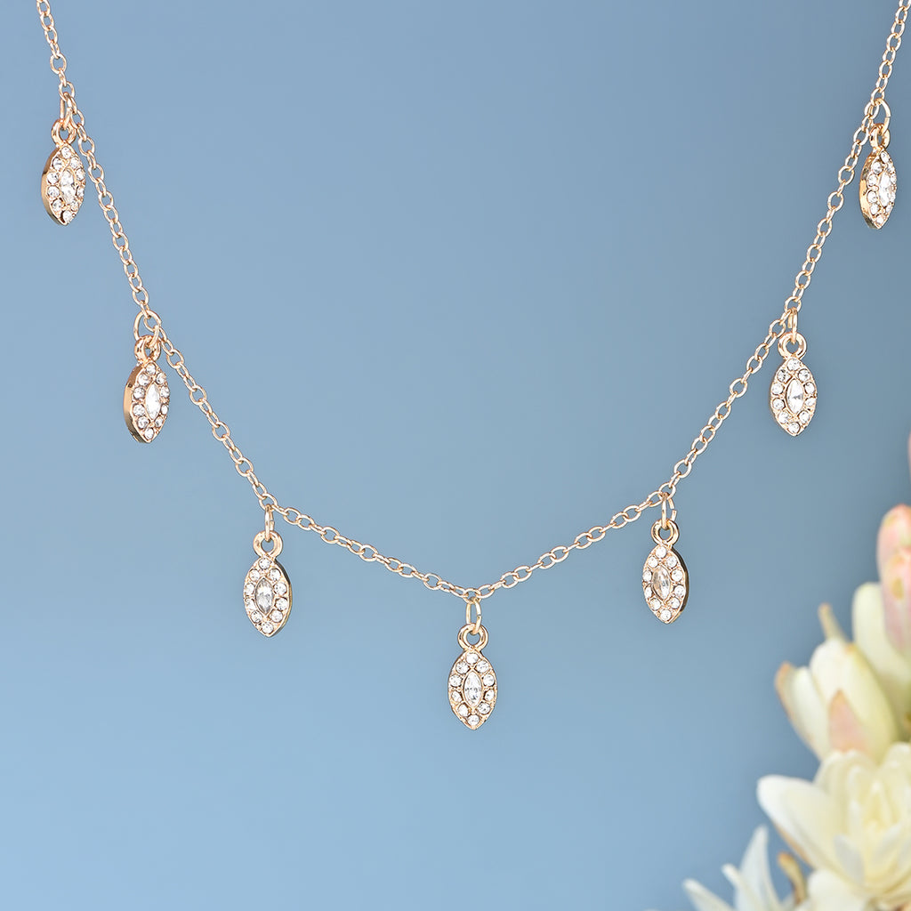 Delicate gold necklace with small diamond-like pendants on a light blue background