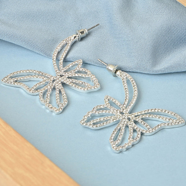 Silver butterfly earrings on a light blue fabric background