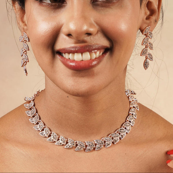 A woman wearing a rose gold plated alloy jewellery set with leafy shapes and studded with American diamonds.