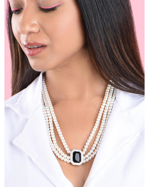 A woman wearing a white shirt and showcasing a white silver-plated pearl necklace with a black crystal stone studded in the center.