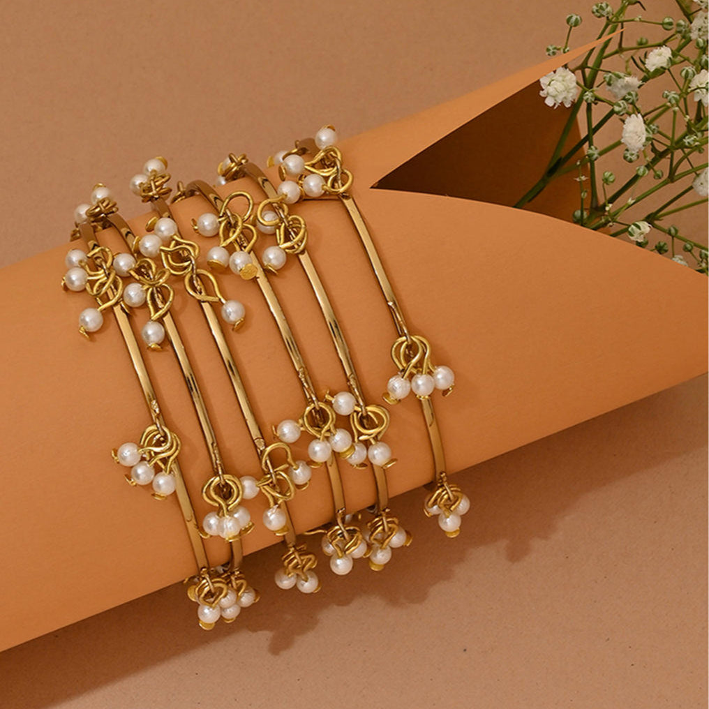 A gold-plated white pearl bangle, featuring a slip-on closure and ornamental pearl drops.