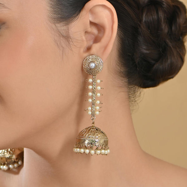 A person wearing gold-toned dome-shaped jhumka earrings with beige beads and a leaf pattern chain.
