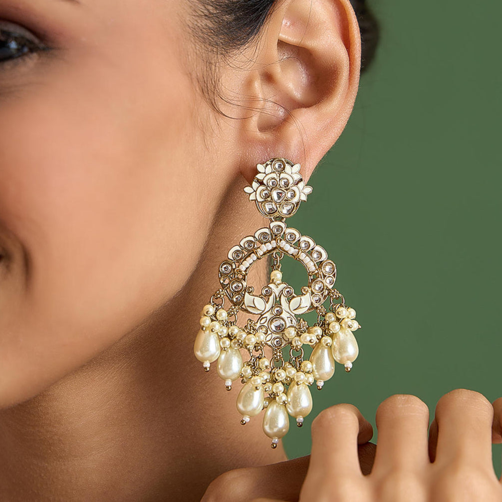 A woman wearing a gold-plated chandbali earring with white meenakari pearls.