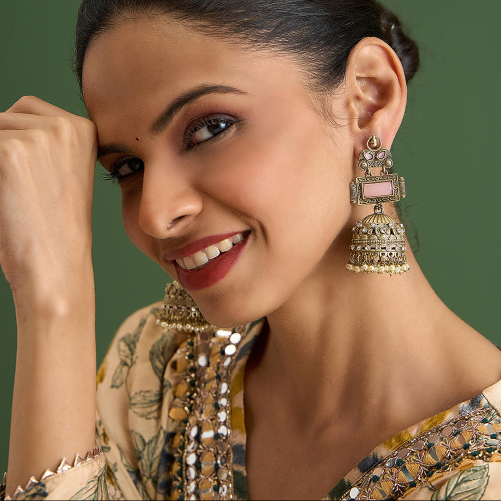 A pair of vintage jhumka earrings with pink accents and white pearl drops