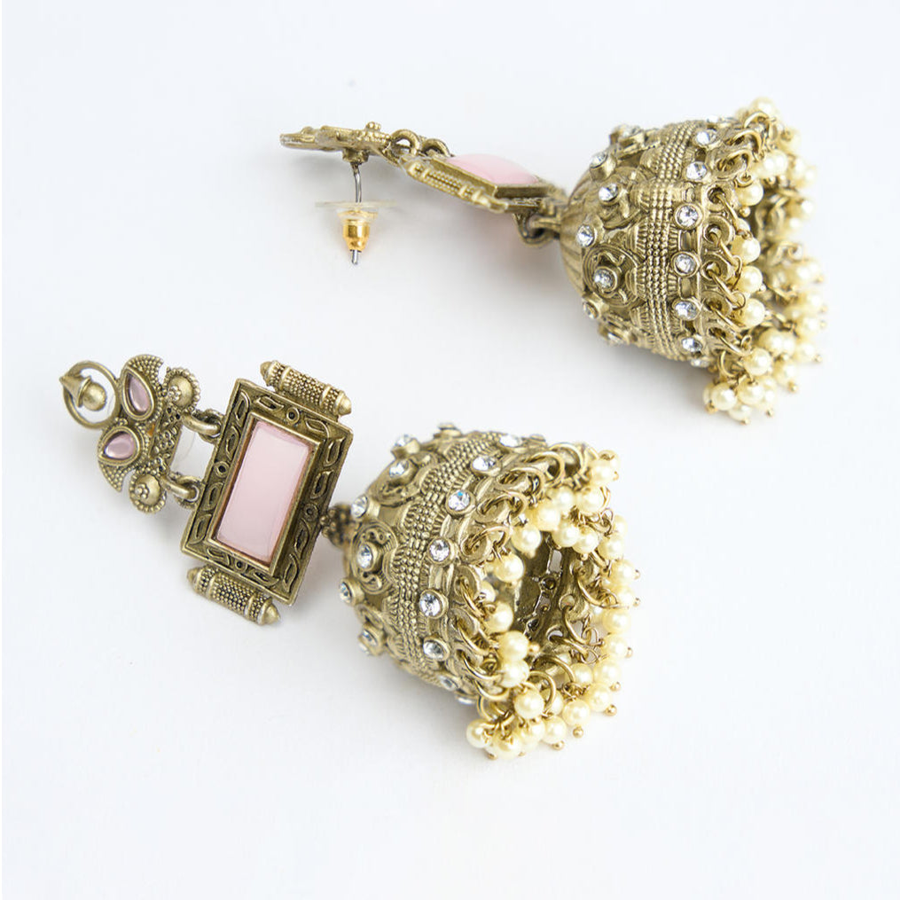 A pair of vintage jhumka earrings with pink accents and white pearl drops