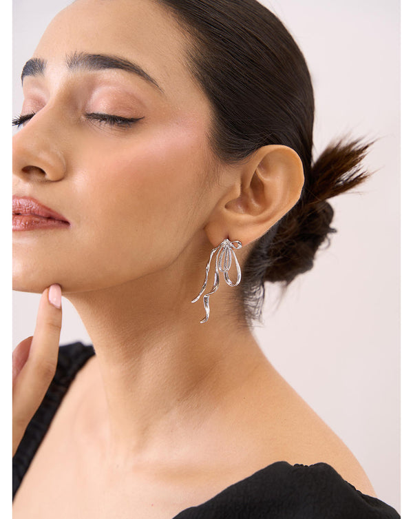 A woman wearing silver contemporary irregular studs earrings, with the earrings being the main focus of the image.