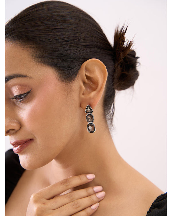 A woman wearing black party drop and dangler earrings with a sleek black design.