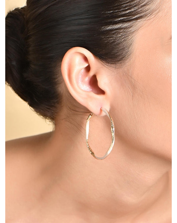 A woman's ear wearing a gold circular hoop earring with lever back closure.