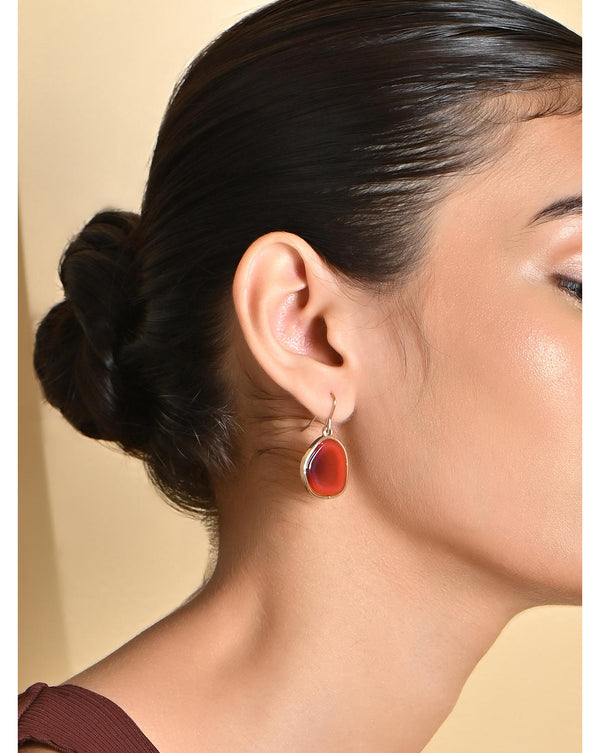 A woman wearing gold maroon drop earrings with fish hook earwire, displayed in an image showcasing the earrings' elegance in a drop style.