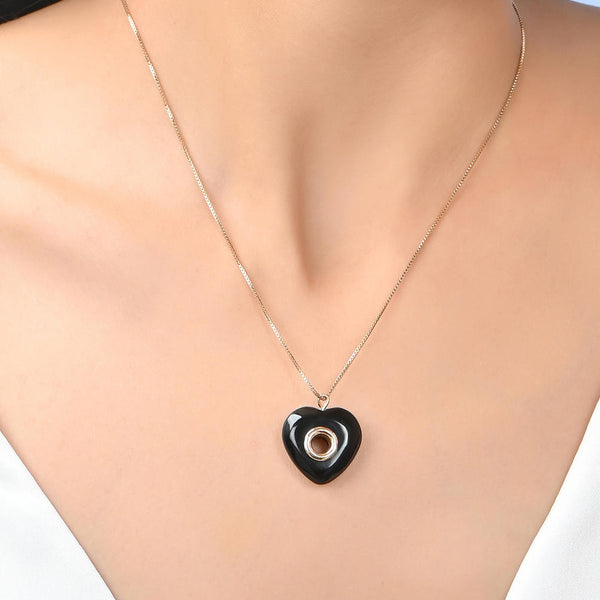 A woman wearing a chic black heart pendant necklace with a gold-toned chain.