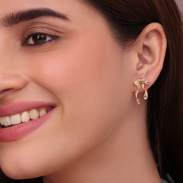 Close-up of a woman wearing a gold earring with a brown background
