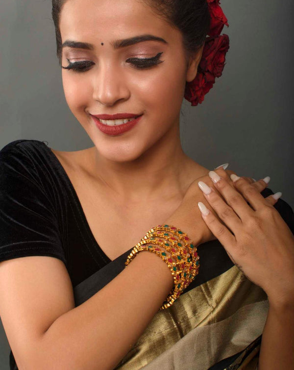 Women wearing Set of 4 gold-plated geometric bangles studded with ruby red and emerald green stones, traditional Indian jewellery for women, perfect for weddings, parties, and festive ethnic outfits